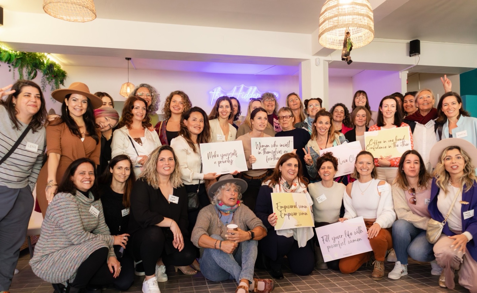 A large group of women from the community holding hand-lettered signs